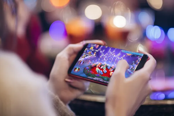 A young woman relaxing with her phone while dynamic casino elements float around her, illustrating the smooth mobile experience offered by the CAWABANGA app.