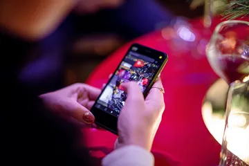 A cheerful woman in traditional clothing using her smartphone during a festive moment, showing how easily the CAWABANGA app fits into everyday life.