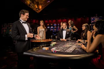 A professional dealer in a tuxedo greeting players at the roulette table, symbolizing the authentic live casino feel at CAWABANGA.
