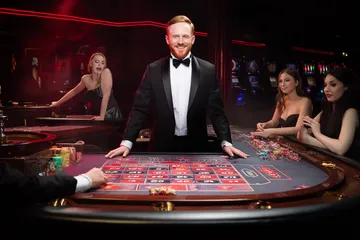 একজন পুরুষ তার ল্যাপটপে জয়ের মুহূর্ত উদযাপন করছেন, চারপাশে ভাসছে গেমিং আইকন—যা CAWABANGA গেমসের উত্তেজনাকে প্রকাশ করে।